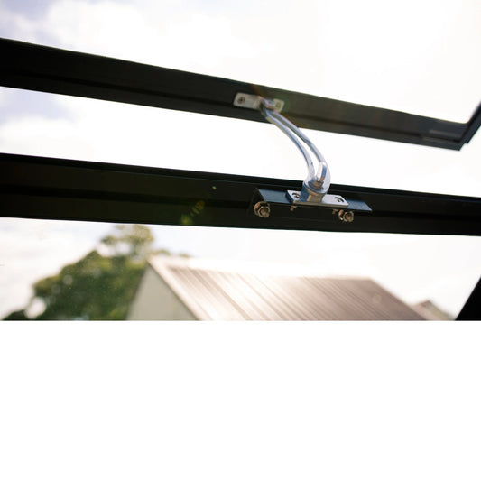 Close-up of a black metal window vent opener with mounting screws against a bright sky background